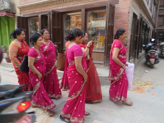 rotgekleidete Frauen auf dem Weg zum Tempel.