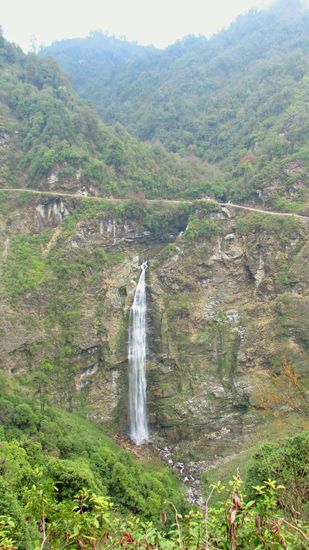 Drüben auf der anderen Seite des Tales fällt ein Wasserfall in die Tiefe. Die Straße führt oberhalb vorbei.