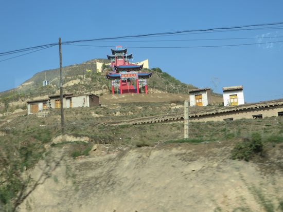 Kleine Tibetanische Klöster liegen am Wegesrand. Sie sind bunt geschmückt mit Gebetsfahnen.