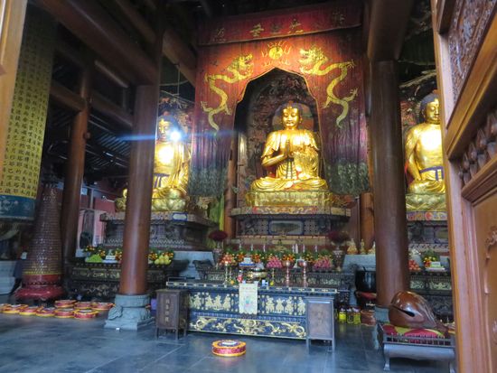 Große goldene Buddhafiguren zieren den Tempel, sie schauen mit mildem Lächeln auf uns herab.