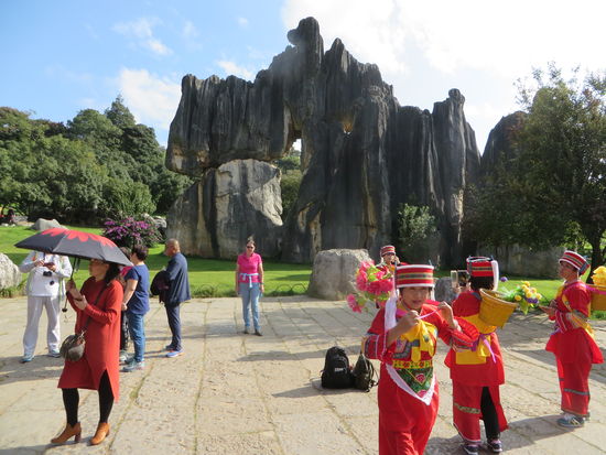 buntgekleidete Menschen (ihre Tracht) lassen sich vor den Steinen fotografieren
