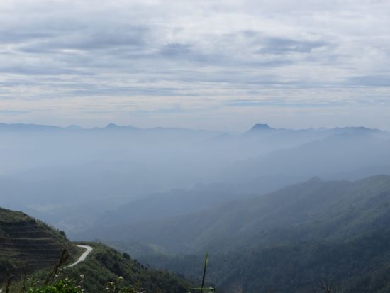 Dunst liegt auf den Bergen. links unten geht die Straße weiter
