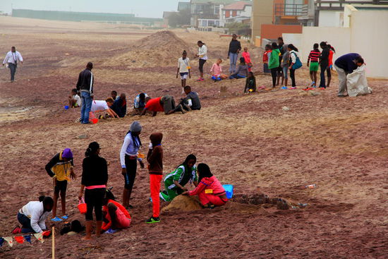 Die farbenfroh angezogenen Kinder scheinen ihren Strand zu genießen, auch wenn das Wetter nicht gerade dazu einlädt