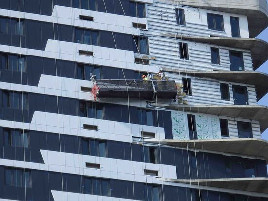 Die Arbeit dieser Fensterputzer machte der Regen zunichte. Die schiefe Gondel hing in der schätzungsweise 10. Etage (mindestens) eines Gebäudes.