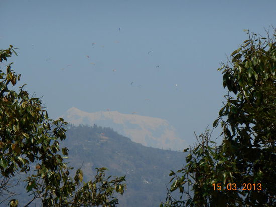 Blick vom Hügel auf einen Teil der Annapurnaberge  - die schwarzen Punkte am Himmel sind Paraglider