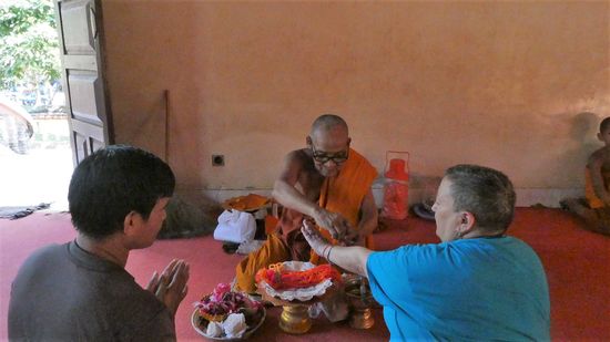 ein Mönch, der gegen kleines Geld ein Bändchen um das Handgelenk bindet, und Gebete für den Menschen ausspricht