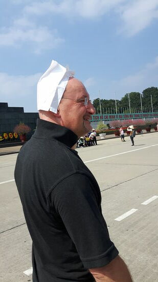 das holländische Meisje. Kappe vergessen, wir improvisieren mit einer Kotztüte aus dem Flieger, die ich seit meiner üblen Erfahrung im Minibus immer mit mir führe.