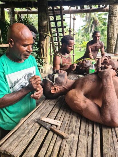 Die Männer werden bemalt, das Malen wird von den anderen übernommen. Hier gibt es ja keine Spiegel