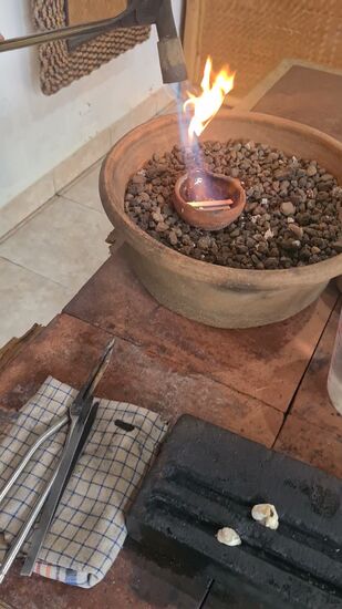 Das Silber wird über einer Flamme erhitzt. Immer schön den Blasebalg treten mit dem Fuss.
Wenn es flüssig ist, wird es in eine kleine Kastenform gegossen.