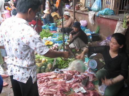 Unser Kochlehrer beim Einkaufen in Battambang (man beachte die frische und gekuehlte Fleischware!)