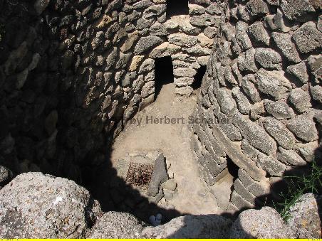 Nach Besteigen der äußeren Mauern kann man in die Innenhöfe an der zentralen Nuraghe hinunterschauen (Brunnen!)