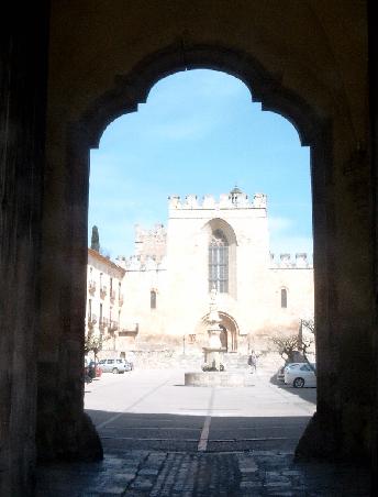 Blick durch die äußere Toranlage auf den länglichen Placa Maior und die romanische Fassade der Kirche
