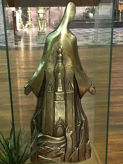 L'ambon montre un Christ dont le Qrand manteau enveloppe l'Eglise vivante aymbollaée par la collégiale. Douze poissons représentant les apôtres sont visibles dans les flots vivifiants de la Meuse. Le poisson est le premier symbole utilisé par les chrétiens du III* siècle pour représenter Jésus. En grec, ICHTUS est l'acronyme de Jésus Christ, Fils de Dieu, Sauveur.