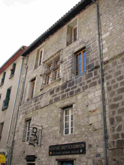 mittelalterliche Fassade mit touristischem Angebot (Grottes und Canyon) und einem Uhrmacher(Schild)