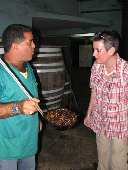Der Arbeiter holt mit einer großen Kelle die in Alkohol-Wasser-Zucker-Gemisch eingelegten Guavenfrüchte aus einer der großen Tonnen zum Probieren