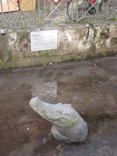 "aus Stein steht hier das Krokodil
mit breitem Maul, doch nicht vom Nil,
schaut raus aus dem Gewerbebach
schaut raus zum Hause Himmelsbach
sieht Euch und uns und denkt sich viel"