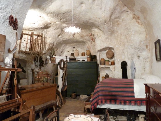 Innenraum mit hohem Bett, Truhe (mit Stroh ausgelegt ebenfalls ein Bett), hinten links ein 'Stall' sowie zahlreiche Nischen.