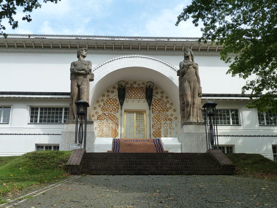 Das Gebäude ist 55 m lang und mit einem schmuckreichen Mittelportal versehen. Zwei Kolossalfiguren flankieren den mit goldverzierten Blütenornamenten versehenen Eingang.