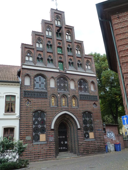 Im Grundriss und Struktur einem gotischen Dielenhaus mit hohem Erdgeschoss und mittigem spitzbogigem Eingang vergleichbar, über dem Eingang drei Nischen, an den Ecken Wappen des Landes und der Stadt unter einem glasierten Laubwerkfries. Der siebenteilige Giebel ist reich mit Taustein verziert, 1886 historisierend rekonstruiert.