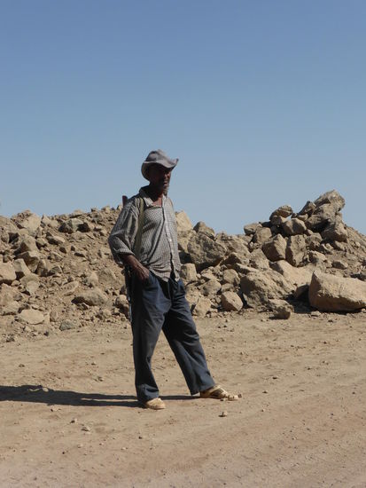 Der Mann mit Gewehr ist, wie sich herausstellt, ein Polizist ohne Uniform.  - aber wen bewacht ode beschützt er?