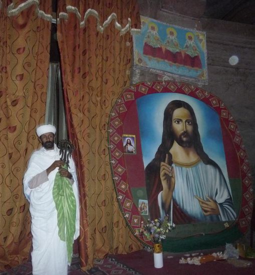 Priester mit Lalibela-Kreuz vor dem Bild des Erlösers