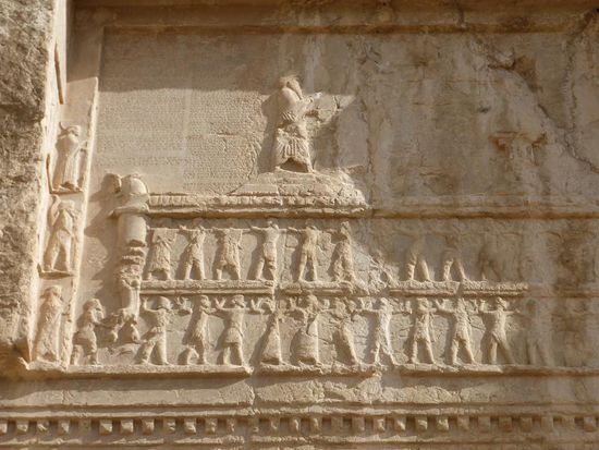 Es sind jeweils eine Palastfassade und ein von Delegierten der Völker gestützter Thron zu sehen, auf dem der König vor einem Feueraltar im Angesicht seines geflügelten Schutzgeistes betet.