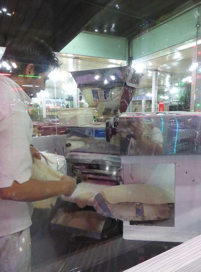 der zu einer dünnen Platte ausgerollkte Teig wird mittels eines Kissens an die Wand eines Ofens 'geklascht', wo er ziemlich sofort Blasen wirft und recht bald 'abgehoben' wird.