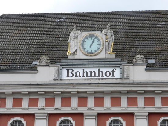 Drahtzieher und Bergmann neben der Bahnhofsuhr stehen als Symbole der Produktivkraft von heimischer Metallindustrie und Zechenansiedlungen vor den alten Stadtgrenzen.