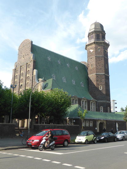 rheinischer Backsteinbau mit grünem Dach  und oktogonalem Glockenturm
