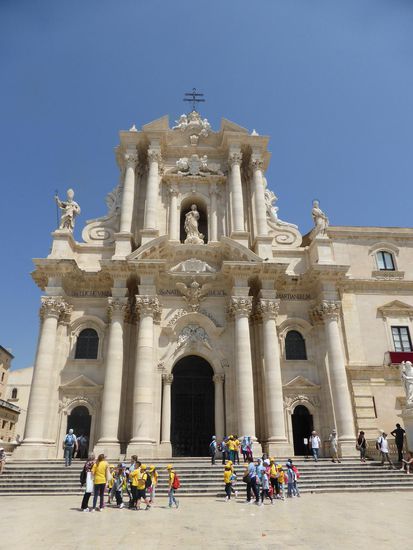 Die breite Freitreppe wird von Statuen der Apostel Petrus und Paulus flankiert, die bewegte Fassadenkulisse von einer beeindruckenden Marienfigur bekrönt.