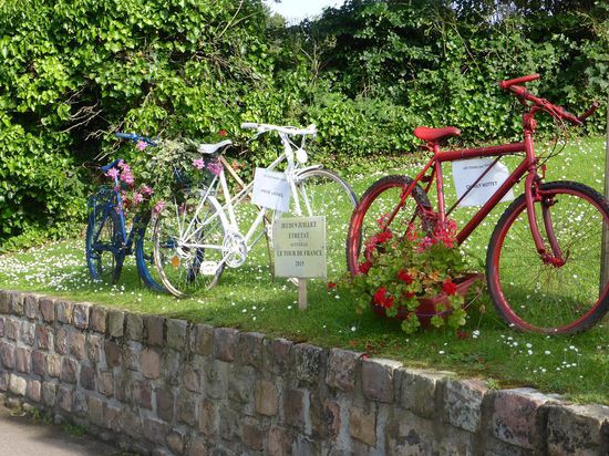 anläßlich der in wenigen Tagen startenden Tour de France sind an der Route der Tour überall alte Fahrräder am Straßenrand dekorativ geschmückt aufgestellt.