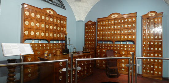 Die eigenwillige Ausstattung kann als Umsetzung der langjährigen Erfahrungen ihres Auftraggebers Faulhaber betrachtet werden: Die alphabtische Beschriftung ermöglichte schnelles Auffinden, die Arzneistoffe selbst waren durch die Türen vor schädlichen äußeren Einflüssen, wie Licht und Ungeziefer, bestens geschützt, und nicht zuletzt beugte die Doppelbeschriftung auf der Türe außen und dem Gefäß innen Verwechslungen nachhaltig vor.
Neben all diesen Vorzügen bestand jedoch ein wesentlicher Nachteil:
Einrichtung entsprach nicht den Vorschriften. Anlässlich einer Apothekenrevision beanstandete der Medizinalrat daher im Jahre 1898, dass die „Standgefäße nicht versteckt hinter Türen stehen dürfen und der Apotheker sie ungehindert greifen müsse"