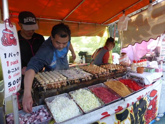 hier werden Halbkugelformen mit Fett gefüllt und  in Teig eingewickelte Tintenfischstücke gebraten