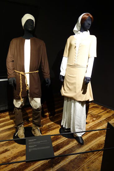 Kleidung einer Bäuerin - 15. Jh.
Leinenhemd, darüber ein geschürztes Kleid mit Schnürung, Pantoffeln und Kopftuch aus Leinen
Kleidung eines Bauern - 15. Jh. 
Knihose, Leinenhemd, darüber eine Jacke (Rock) mit gedrehtem Gürtel aus Hanf, Beinlinge, Stiefel, auf dem Kopf eine Mütze aus Wolle