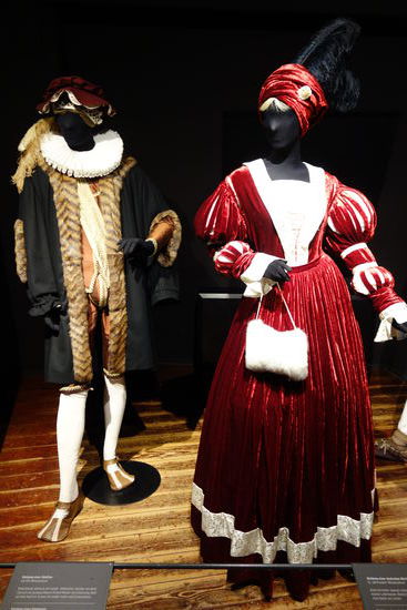 Kleidung einer Edelfrau - um 1514 (Renaissance)
Brokathemd, Reifrock mit Gesäß-, Hüftpolster, darüber ein Kleid (Surcot)  mit austauschbaren Ärmeln, Mieder mit Schnüruog, Muff, auf dem Köpf ein Turban mit weißer Feder und Schmuckstein
Kleidg eines Edelmanns - um 1520 (Renaissance)
Hemd mit Mühlsteinkragen, darüber eine Jacke (Wams), Kniehose mit Schamkapsel (Braguette) und eine Pelz verbrämte Schaube (Zimarra), bestickte Seidenstrümpfe, Kuhmaulschuhe, auf dem Kopf ein Barett mit Federschmuck am Rand geschlitzt, darunter eine Haube (Calotte)