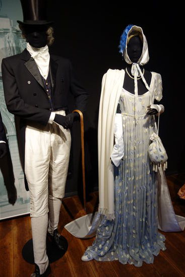Frauenkleidung - 1804 - Empire
fleischfarbnenes Hemd (Trikot), darüber ein Kleid aus Musselin mit Schleppe, hoch gesetzter mit Gürtl betonter Taille, dazu lange bis zu den Oberarmen reichende Handschuhe, ein langer Schal ergänzt die luftige Kleidung, Pompadour (kleine Tasche), absatzlose leichte Schuhe, auf dem Kopf eine Haube, mit Federn geschmückt. 
Männerkleidung - 1804 - napoleonische Zeit
Hemd mit hochgestelltem Kragen (Vatermörderkragen), weiße Seidenwestemit Hose und eine brokatfarbene Weste, darüber ein schwarzer Frack mit spiegelseidenen Revers. bestickte Seidenstrümpfe, schwarze Halbschuhe, Zylinder.