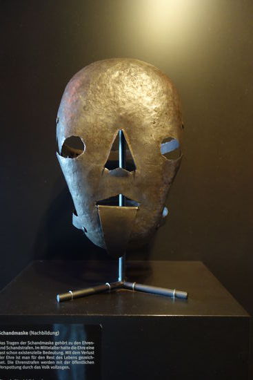 Schandmaske - das Tragen der Schandmaske gehört zu den Ehren-und Schandstrafen. Im Mittelatter hatte die Ehre eine fast schon existenzielle Bedeutung. Mit dem Vertust der Ehre ist man für den Rest des Lebens gezeichnet. Die Ehrenstrafen werden mit der öffentlichen Verspottung durch das Volk vollzogen.