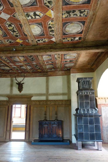 Die farbenprächtige Ausmalung gab der Roten Stube ihren Namen. Sie war über einen großen Kachelofen beheizbar und diente auch deshalb als Hauptwohnraum. Im Zuge der Verwüstungen des Dreißigjährigen Krieges wurde auch der Kachelofen zerstört. Anhand einzelner Kachelfunde war es jedoch möglich, den Ofen nachzubauen.