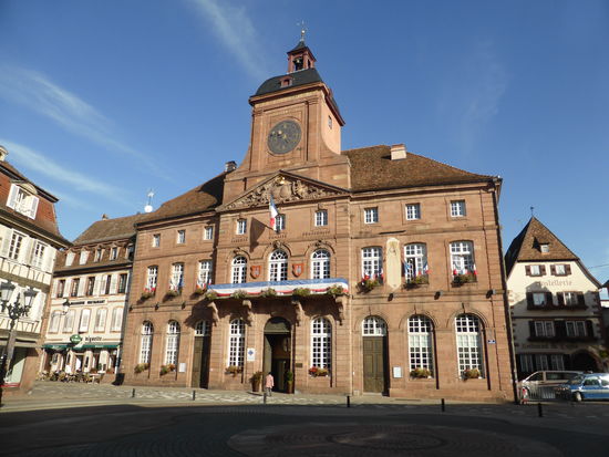 Der Erbauer des Rathauses war Joseph Massal. Der Bau (1741 - 1752) sollte das während des grossen Stadtbrandes (26.01.1677) zerstörte Rathaus ersetzen. 
Über dem Zifferblatt befindet sich eine lateinische Inschrift: « Unter der Herrschaft Ludwig XV. bin ich aus alter Asche neu entstanden.»