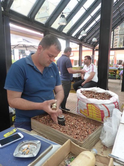 auf einem kleinen Amboss befreit dieser Herr die Haselnüsse von der Schale - ob er heute fertig wird?