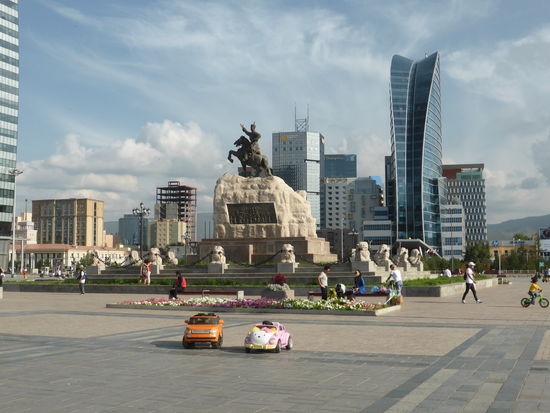 Reiterdenkmals Dschingis Khans vor der modernen Kulisse von Hotels und Kaufhäusern - sehr beliebt z.Zt.: kleine Automodelle, in denen Kinder fahren können