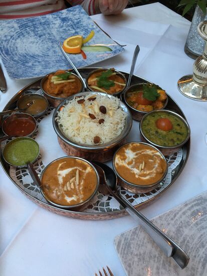 es besteht aus zwei Fleischgerichten (Huhn und Lamm)  und einem vegetarisches Gericht, dazu Linsen-Curry, Knoblauch und Ingwer, verschiedene Chutneys, Basmati-Reis, Chapatis und Naan-Brot