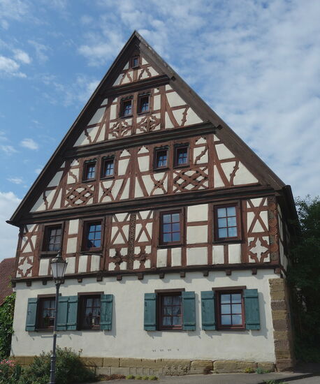 als Wohnhaus 1597 mit Zierfachwerk und geschnitztem Eckbalken sowie iner Scheune erbaut