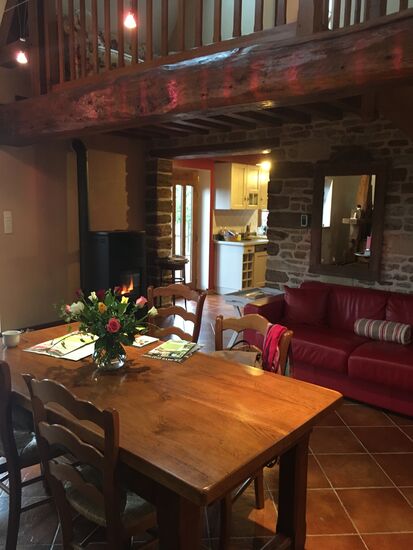 Wohnzimmer mit großem Tisch und Ledersofa - für kalte Tage gibt es einen Pelletofen, der wohlige Wärme verteilt.