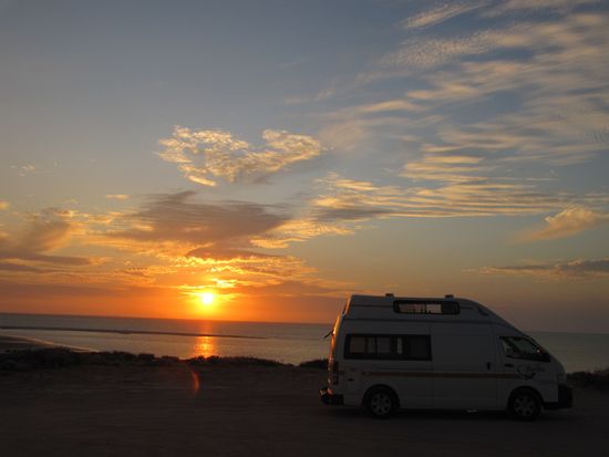 ... bei Sonnenuntergang, mutterseelen allein im Nirgendwo. Nach Sonnenuntergang fahren selbst auf der Strasse keine Autos mehr. Erstes Kochen im Britz. Da muss ich erstmal richtig lernen, wie ich das am besten organisiere. Wo ist was verstaut, bei dem wenigen Platz. Aber mit den Tagen gewöhnen wir uns, das Schlafen ist echt gemütlich, nur das fehlende Bad (Toilette!!!) stört. Um 19:00 Uhr ist es dunkel, ein wenig lesen und dann ist Schlafenszeit. Morgens geht es früh weiter. Um 6:30 muss ich schon mal die Bucht ablaufen. Ganze Muschelwege gibt es hier. Aber so früh bei Ebbe läßt sich kein Shark blicken. Schade. Beim Frühstück kommt schon ein Besucher auf unseren  Parkplatz. Dann nehmen wir Abschied von unserer 1. Nacht in der Wildnis.