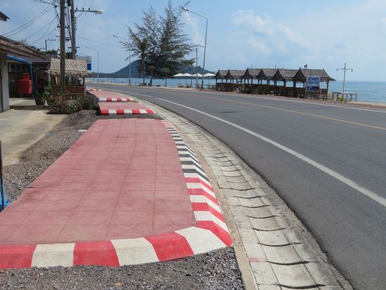 Im Dorf sind die Straßen neu gemacht und überall gibt es neue, rote Bürgersteige, die allerdings nur von Touristen, hier Farangs, genutzt werden. Warum? Weil Thais nicht zu Fuß gehen. Man fährt Auto, gerne große Pickups, oder mindestens zu Viert auf dem Motorrad. Ansonsten ruft man gerne über die Straße oder durch die Bretterwand, damit der Nachbar nicht extra zum Gartenzaun kommen muß.