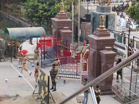 Im Bild: das rote indische und das graue pakistanische Grenztor. Beide werden kurz geöffnet und 2 (gegnerische) Offiziere geben sich tatsächlich die Hand. Beide Tore werden wieder geschlossen. 
PS. Das pakistanische Tor sieht etwas imposanter und stabiler aus. Dafür sind Geschrei und Emotionen auf indischer Seite allerdings nicht zu überbieten.