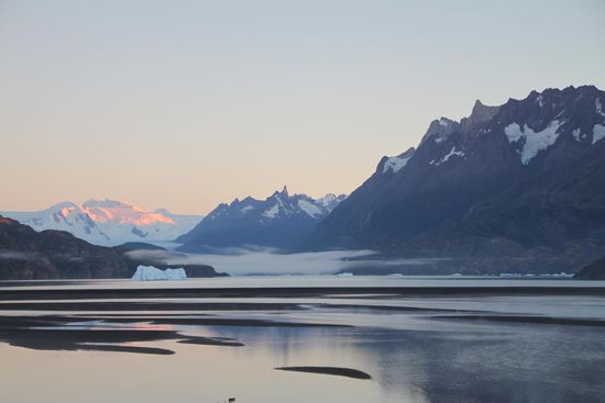 Die ersten Sonnenstrahlen des nächsten Morgens zaubern einen rosa Schimmer auf den Gletscherberg. Aber warum versteckt der sich denn an einem so strahlenden Tag unter einem Tischtuch aus Nebel?