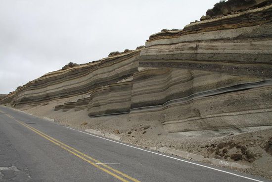 Geologie for Beginners: An dieser Stelle sieht man sehr anschaulich, wie hier zwei tektonische Platten aufeinander stoßen. Vom Ozean im Westen schiebt sich die Nazca-Platte (im Bild von links kommend) unter die Südamerikanische Platte, auf der der gesamten lateinamerikanischen Kontinent "ruht".
Durch diese Plattenverschiebung, die kontinuierlich weiterhin stattfindet, ist es in diesem Gebiet natürlich alles andere als ruhig. Nicht umsonst befinden sich so viele und vor allem die höchsten Vulkane der Erde genau hier und auch Erdbeben sind in Südamerika entlang der Platten keine Seltenheit.
Die gesamten Anden sind das Produkt der Plattenverschiebung. In den einzelnen Sedimentschichten könnte ein echter Geologe bestimmt total spannende Dinge ablesen. Wir belassen es dabei, dass wir uns sagen, dass wir die grau bis schwarzen Schichten wohl Ausbrüche des Chimborazos gewesen sein müssen