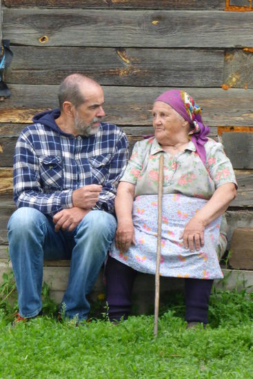 Begegnungen: Valentina sitzt vor ihrem Anwesen und beobachtet das dörfliche Treiben